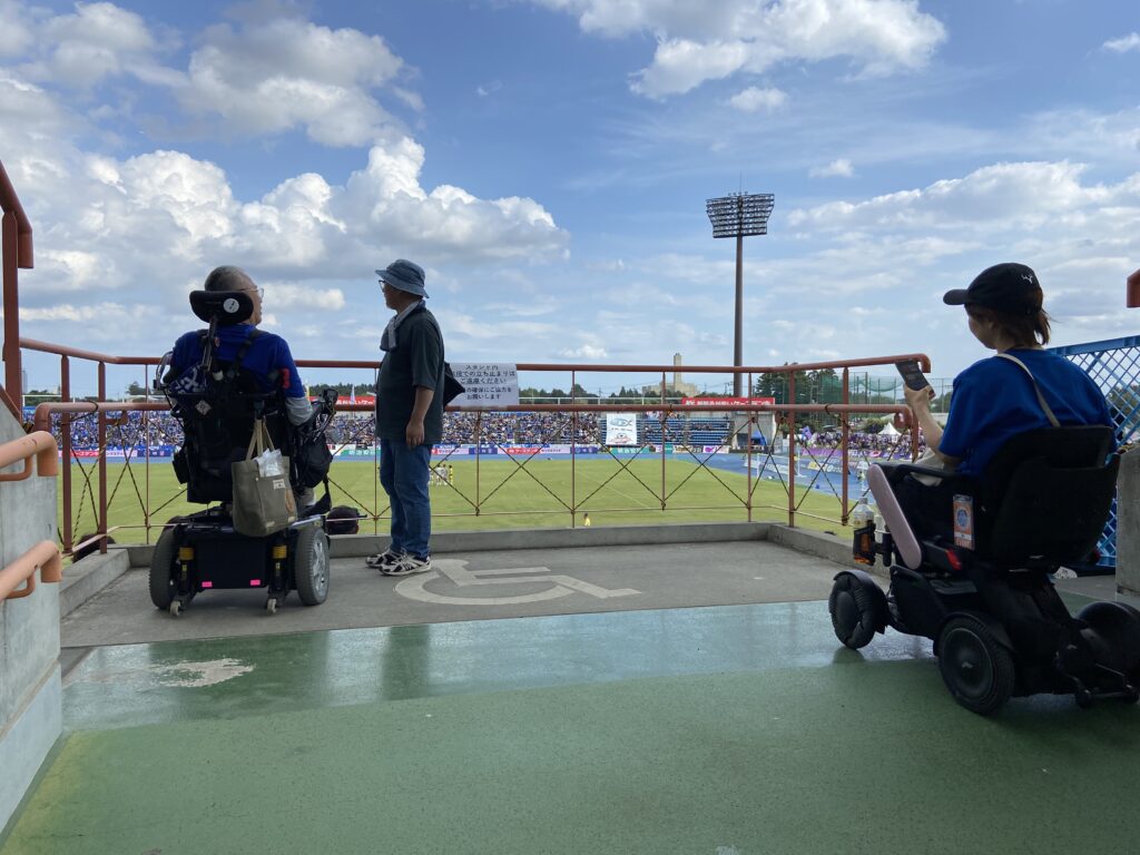 メインスタジアムの車椅子席の様子
客席がないフラットなスペースがあり、前列の観客が立ち上がっても車椅子の人の視界は遮らないようになっている。ただ、転落防止の手すりが視界を遮る高さに設置されている。