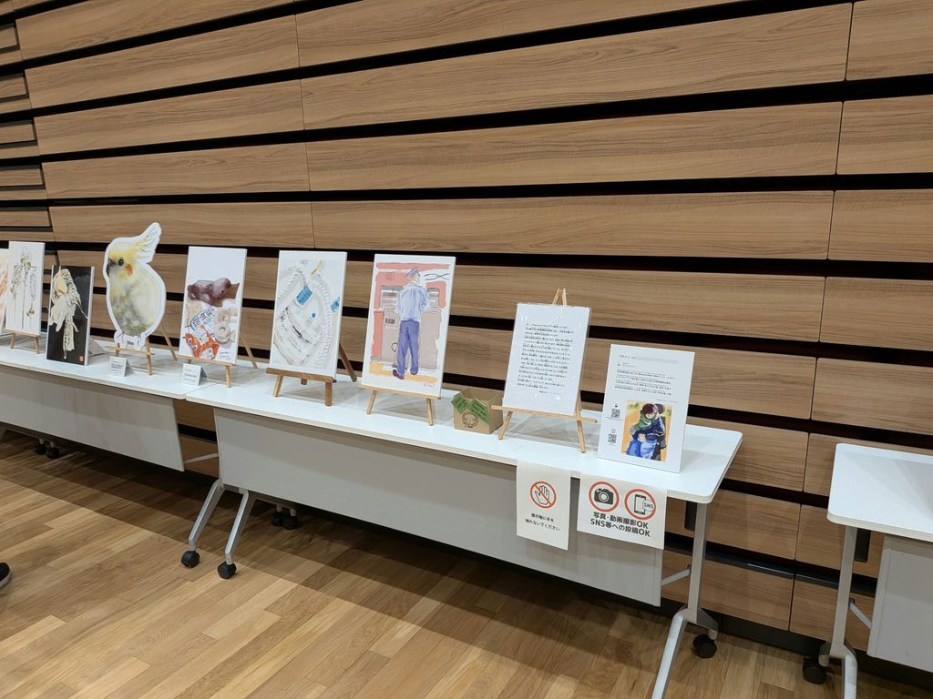佐藤裕美さんの作品　電車に乗る時のスロープを持った駅員の絵など、日常の様子が描かれている