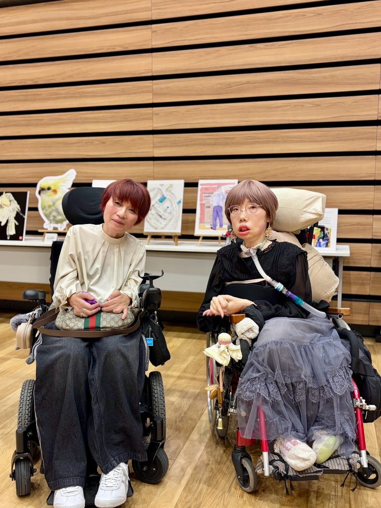 佐藤裕美さんと辻友紀子さんが自分が描いた作品を背景に２ショットで写っている。